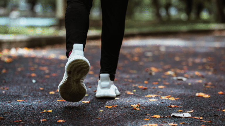 Close-up photo of the foot and calf of someone with running shoes jogging on the park
